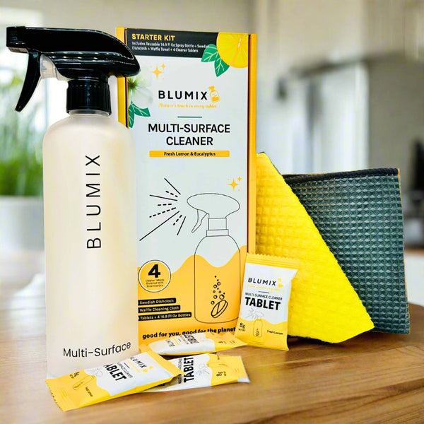 A starter kit for multi-surface cleaning by Blumix, including a spray bottle, essential oil-infused tablets, a yellow Swedish dishcloth, and a grey waffle weave cloth